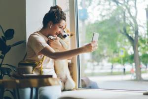 a smiling woman taking a selfie with her shiba inu dog